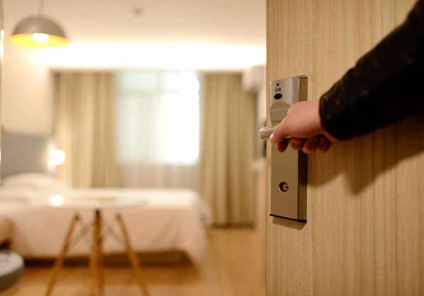 A person opens the door to a hotel room where plumbing is installed