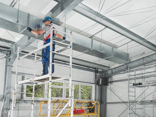 Professional HVAC Worker on a Scaffolding Installing Air Duct