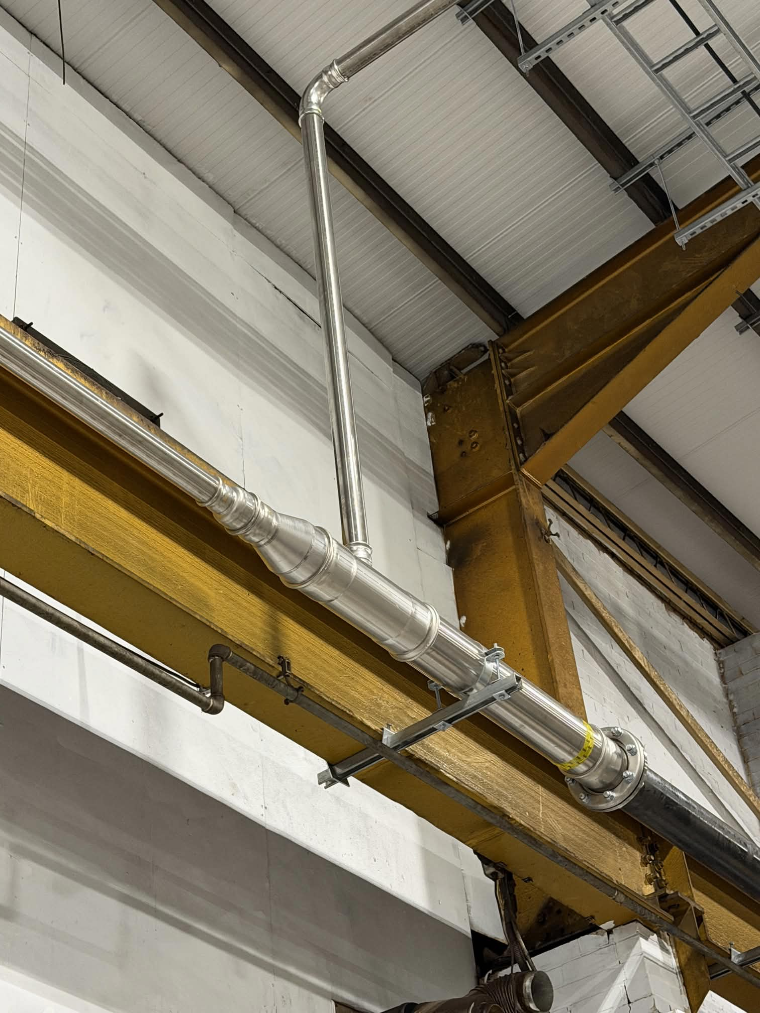 Stainless steel 6 inch gas pipework suspended from overhead structural steelwork during installation